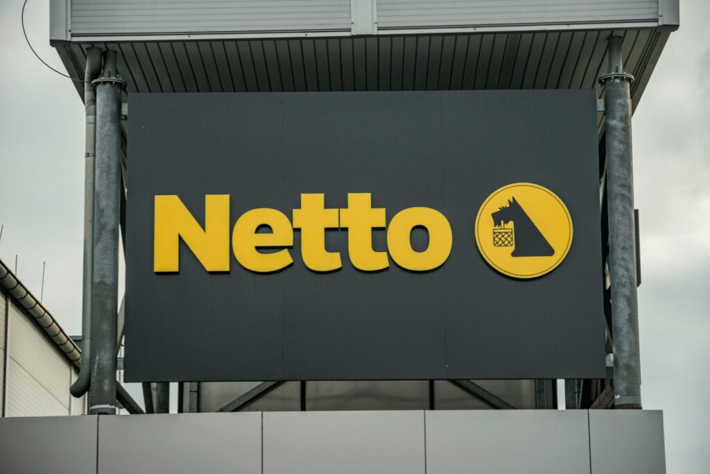 Exterior view of Netto supermarket branding, featuring yellow logo on dark background.